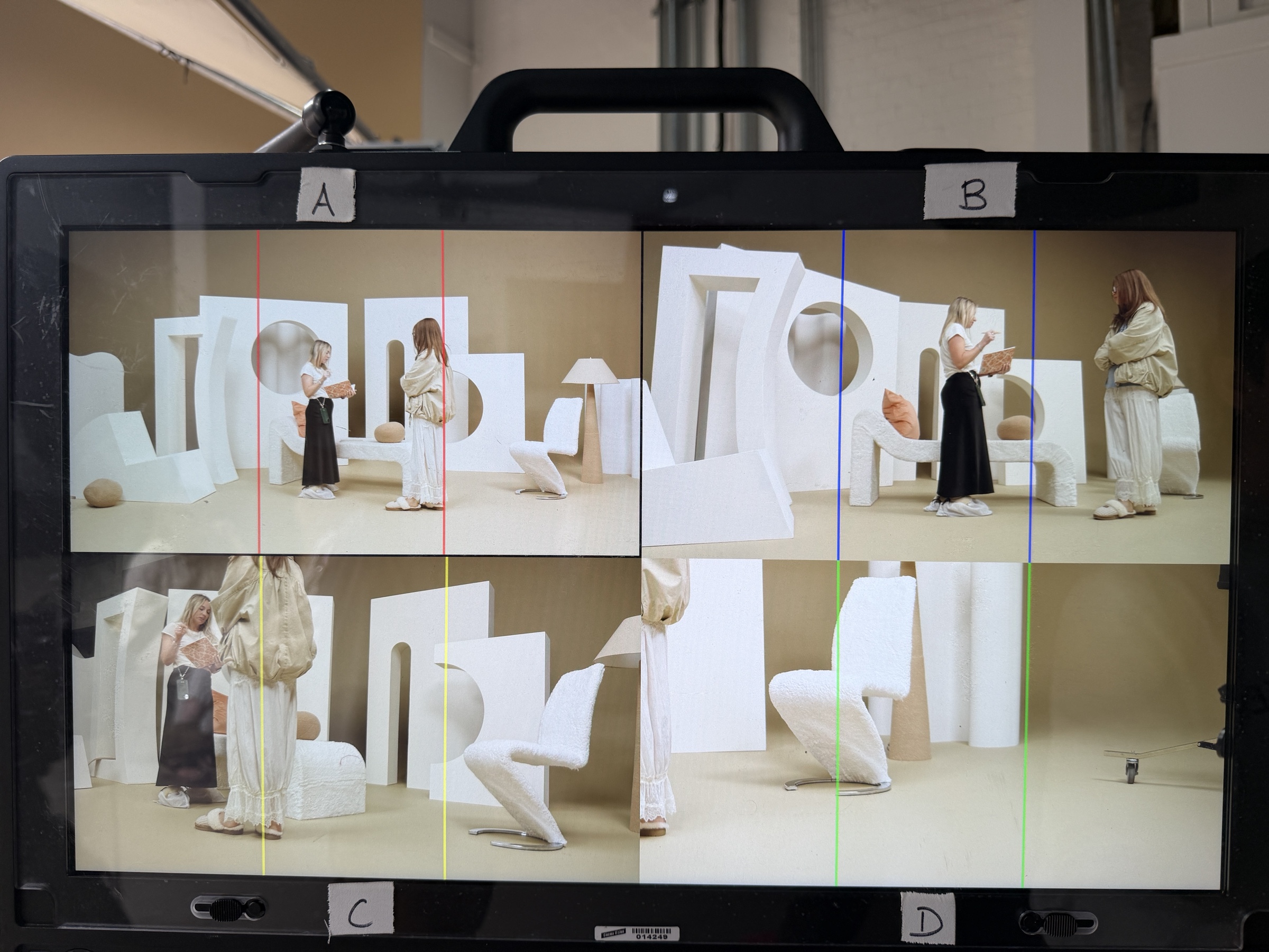 Director's monitor showing four camera views of the sculptural white lounge set